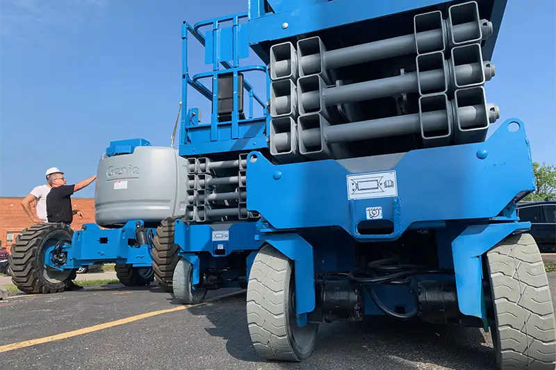 Refurbished Genie electric scissor lift being inspected outdoors by technician